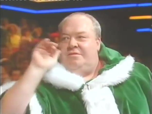 Leighton Rees throwing darts on Bullseye dressed as a green Father Christmas