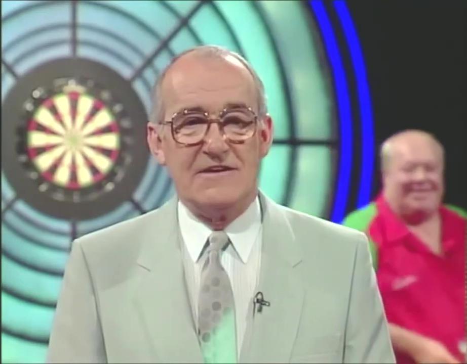 Jim Bowen talking to the camera with Leighton Rees in the background