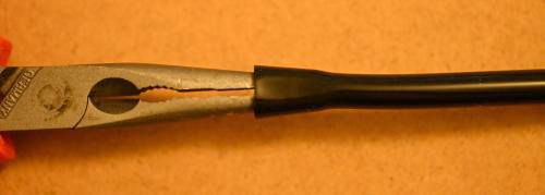[a pair of pliers pushing open the hole at the end of the tubing]