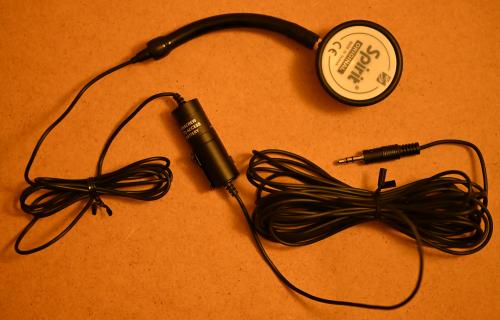 [the metal end of a stethoscope with a microphone inserted into it]